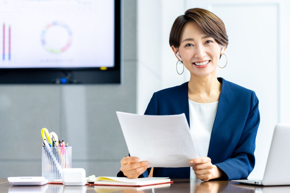 書類を見ながらにこやかに仕事をする女性ビジネスマン